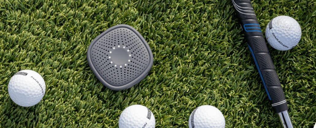 A relay device on a golf course next to golf balls.