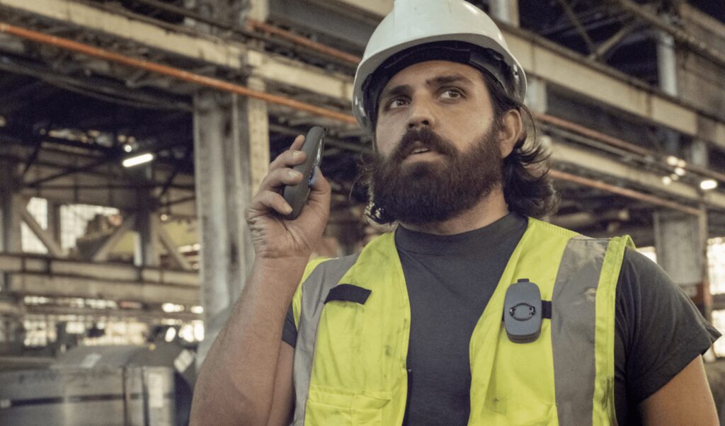 A manufacturing worker listening to someone speak to them via RelayX