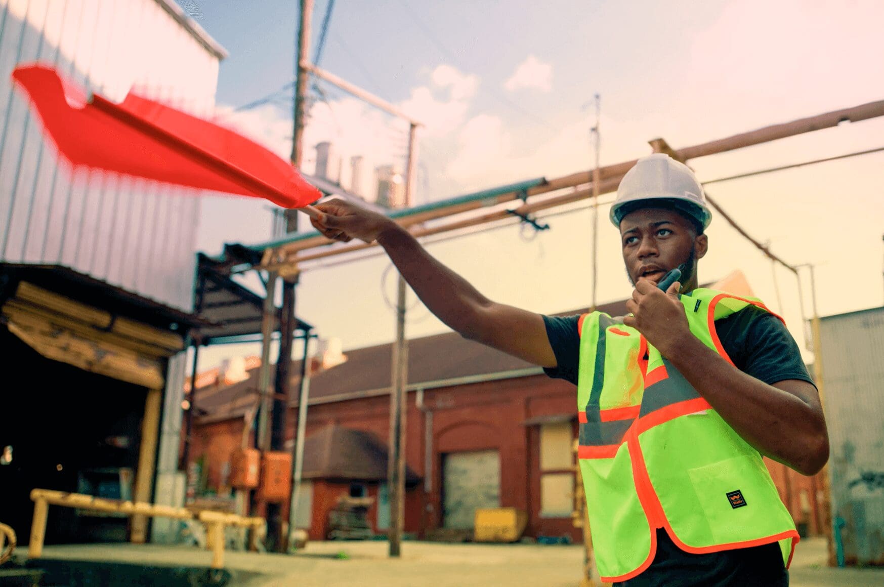 Industrial employee in neon vest waving flag, while using RelayX