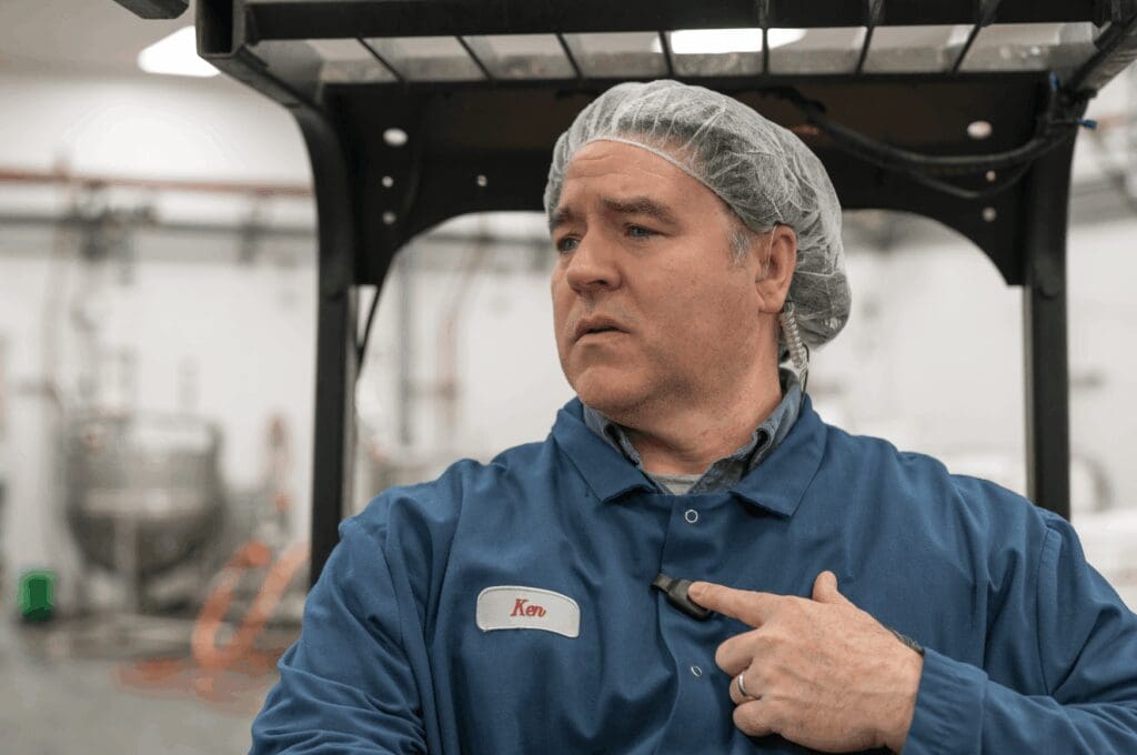 Man wearing hairnet in warehouse, communicating via RelayX mic from a forklift