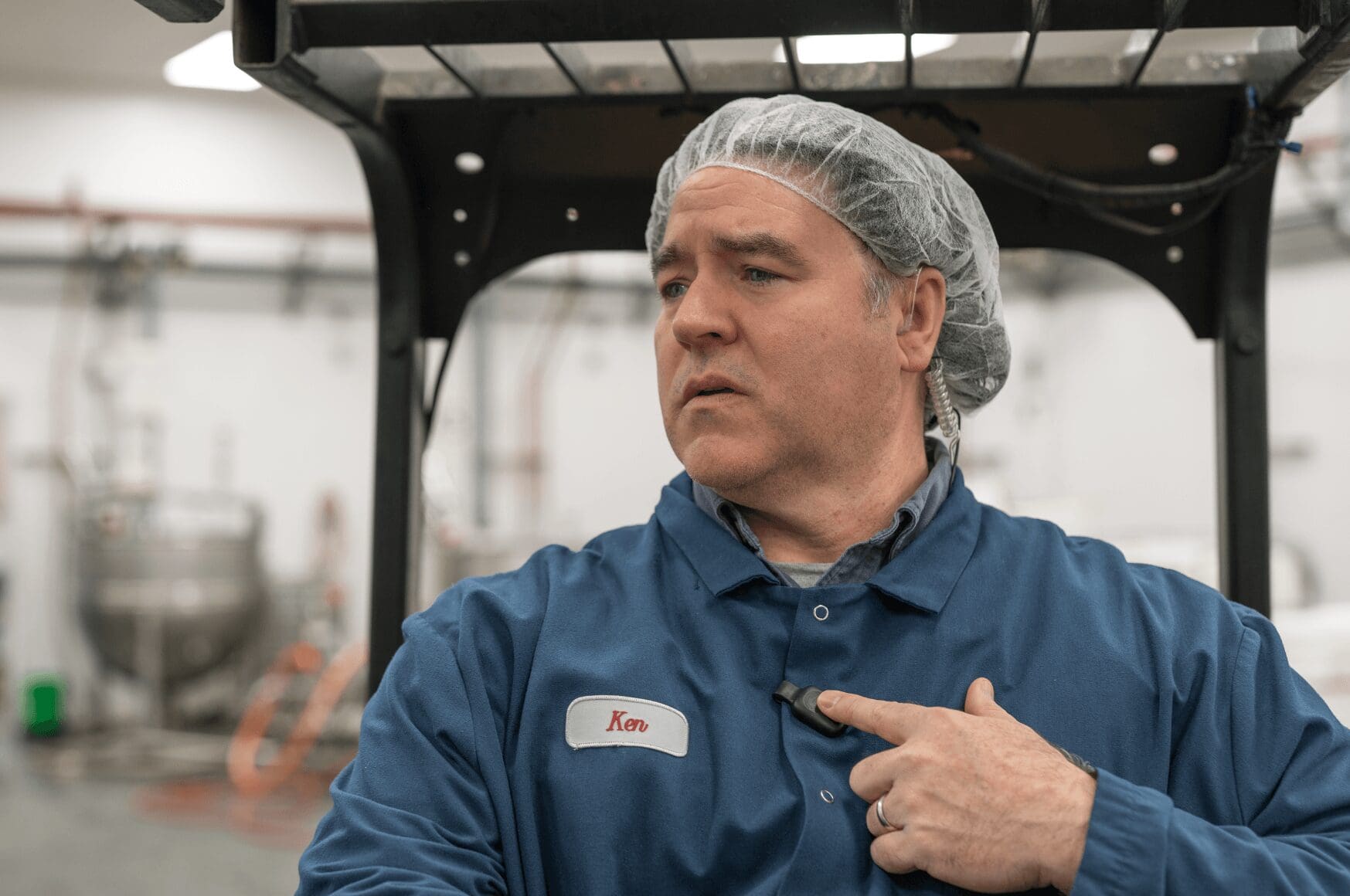 Man wearing hairnet in warehouse, communicating via RelayX mic from a forklift