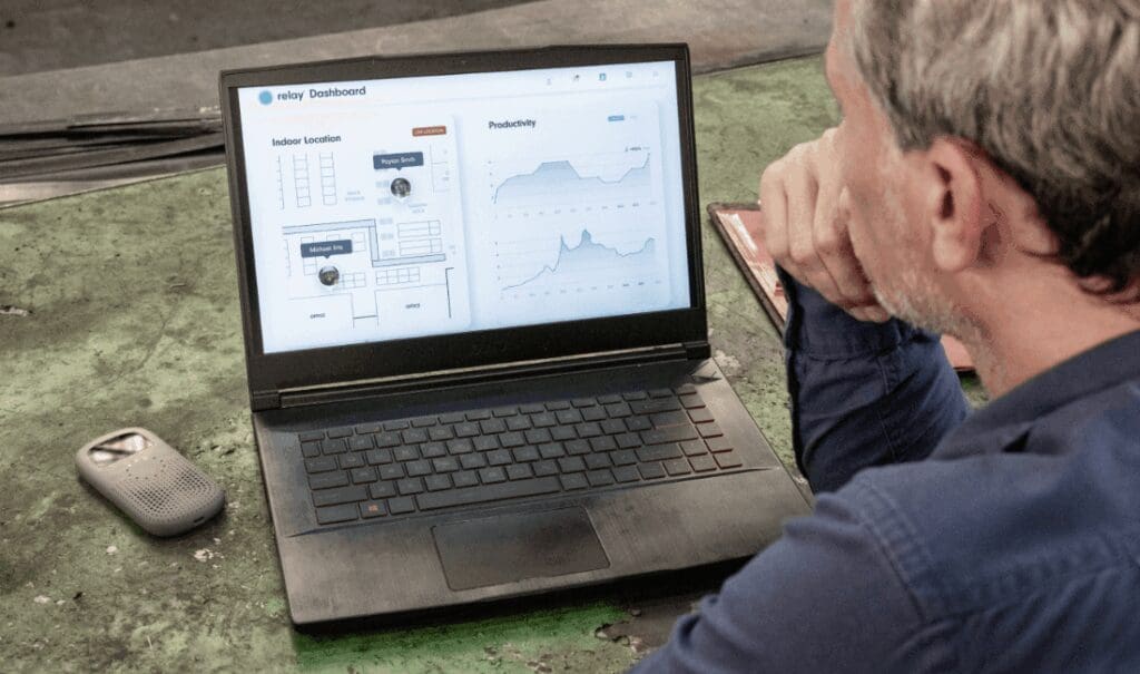 Factory manager reviews location tracking and productivity data on the Relay Dashboard displayed on a laptop, with a Relay device resting nearby.