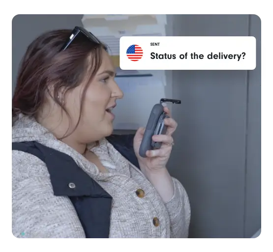 A woman uses a Relay device to ask, “Status of the delivery?” inside a food manufacturing facility.