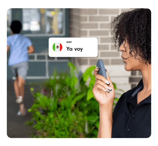 A school staff member uses a Relay device outdoors as a student runs toward a building, with a message saying “Ya voy.”