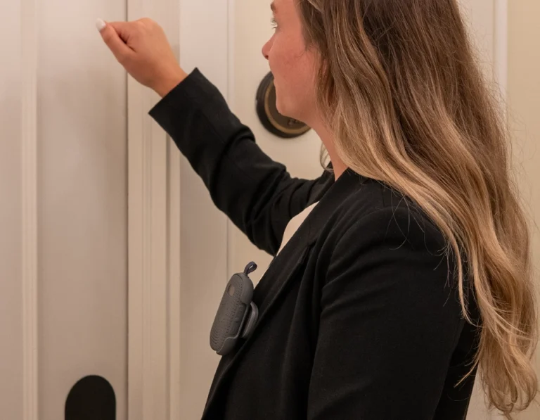 Hotel employee wearing a RelayM device on their blazer while knocking on a guest room door.