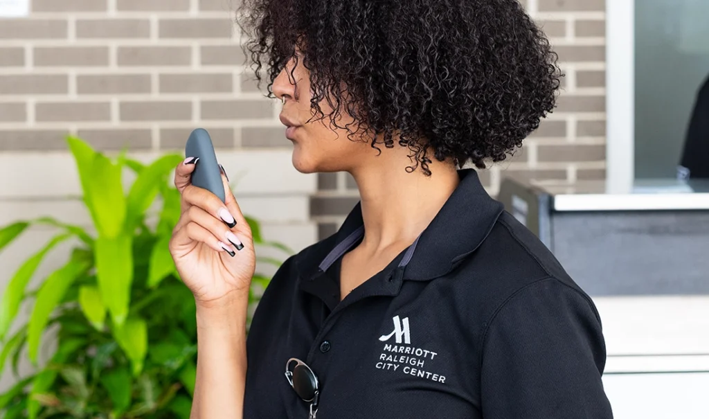 Hotel staff member at Marriott Raleigh City Center communicates using a RelayM device outside the building.