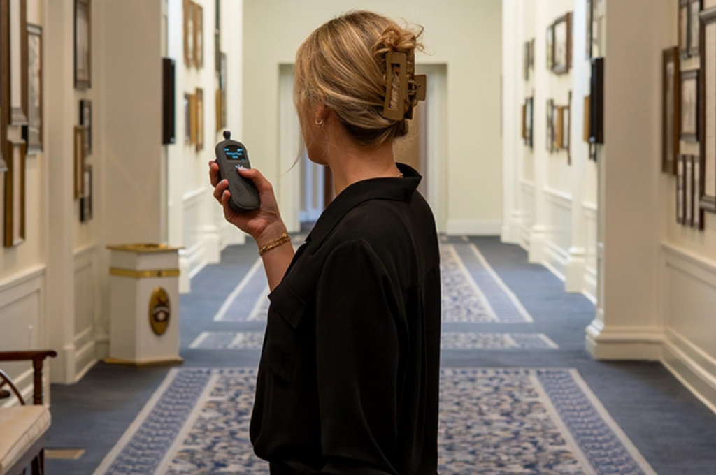 Woman dressed in black holding RelayX in hotel hallway