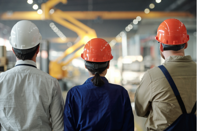 Three manufacturing employees reviewing operations on the factory floor, representing manufacturing employee engagement in action