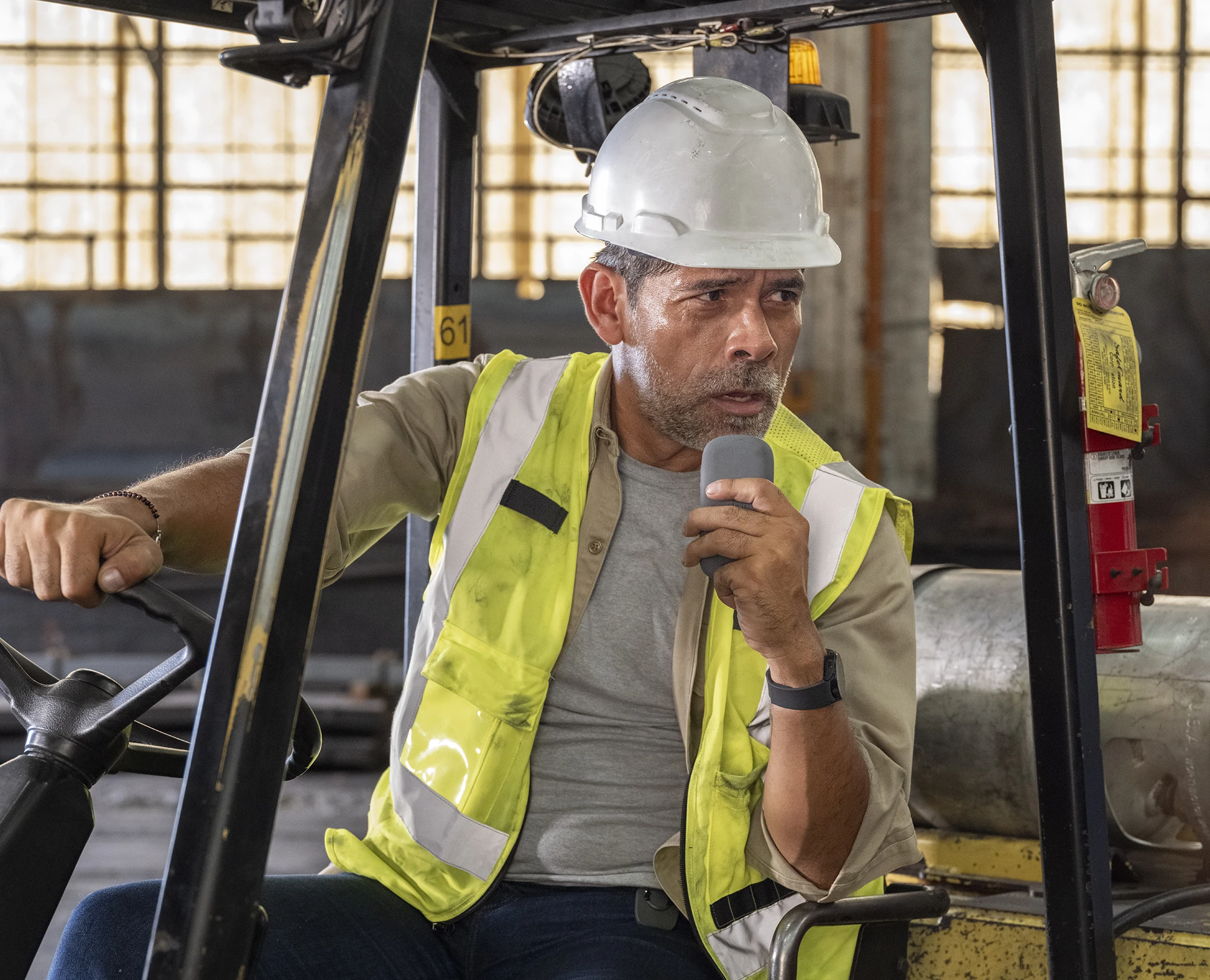 Worker speaking into a Relay radio, hands full, mid-task